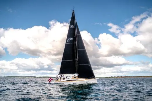 Slide: The Image of 2024 X-Yachts X4-0 sailing on open water under a blue sky with clouds. - 6