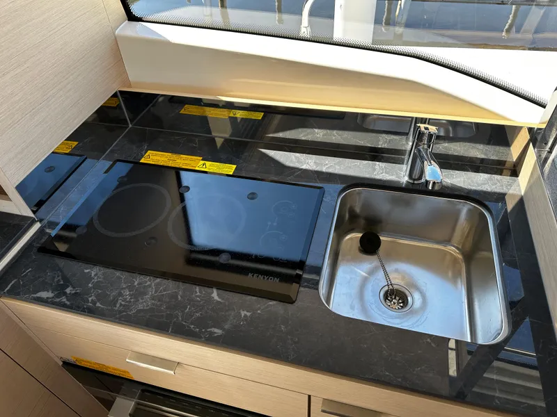 Slide: The Image of Prestige 420S 2024 yacht kitchen with black marble countertop, sink, and induction cooktop. - 28