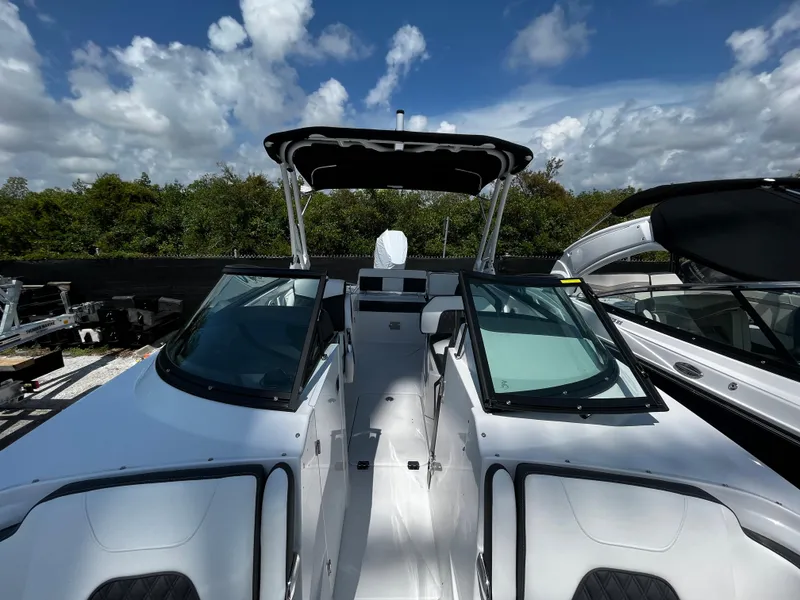 Slide: The Image of 2024 Monterey M-65 boat with dual windshields and canopy, docked under a partly cloudy sky. - 21