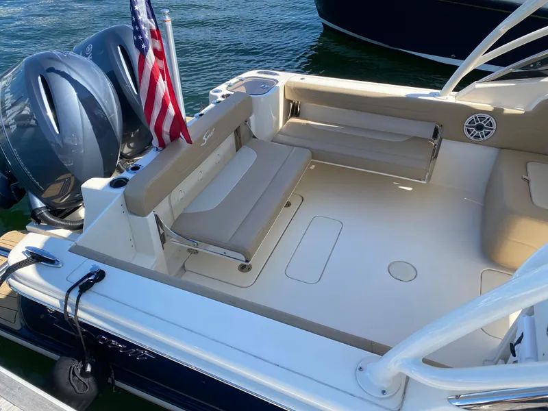 Slide: The Image of 2022 Scout 255 Dorado boat with beige seating and twin engines docked by the water. - 6
