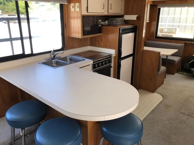 Slide: The Image of 1993 Gibson 37 Sport Series kitchen with bar stools, sink, stove, and dining area. - 12