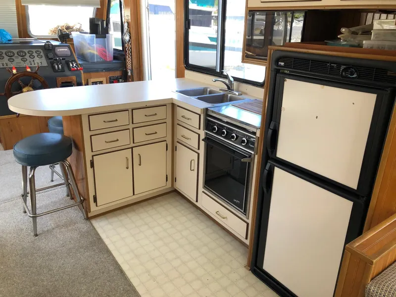 Slide: The Image of 1993 Gibson 37 Sport Series boat kitchen with stove, sink, fridge, and counter seating. - 13