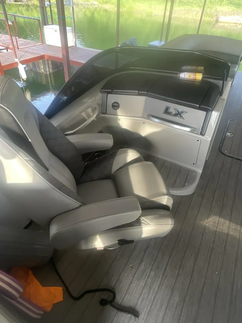 Slide: The Image of 2021 Manitou 27 LX SRW Duel Engine boat interior with captain's chair and control panel. - 7