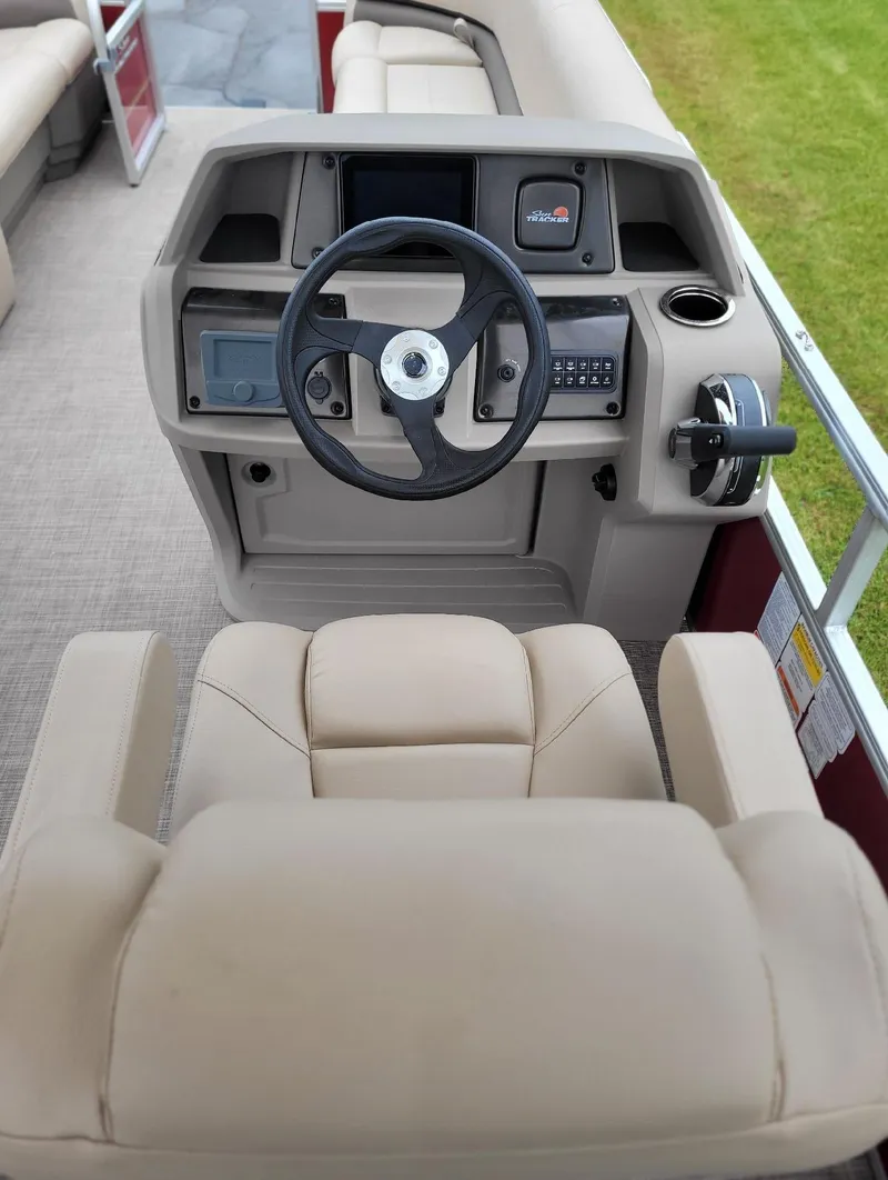 Slide: The Image of 2024 Sun Tracker Party Barge 18 DLX helm with beige captain's chair and steering console. - 3