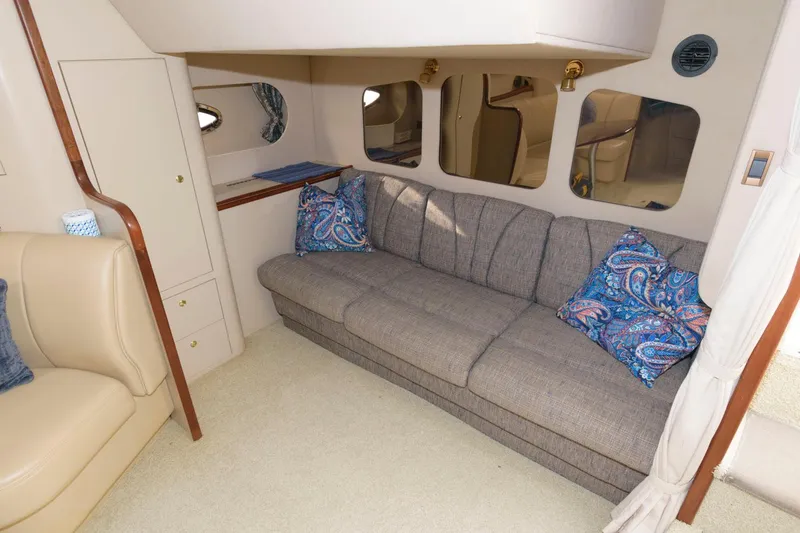 Slide: The Image of Interior of 2000 Cruisers Yachts 3672 Express with gray sofa and blue patterned pillows. - 17