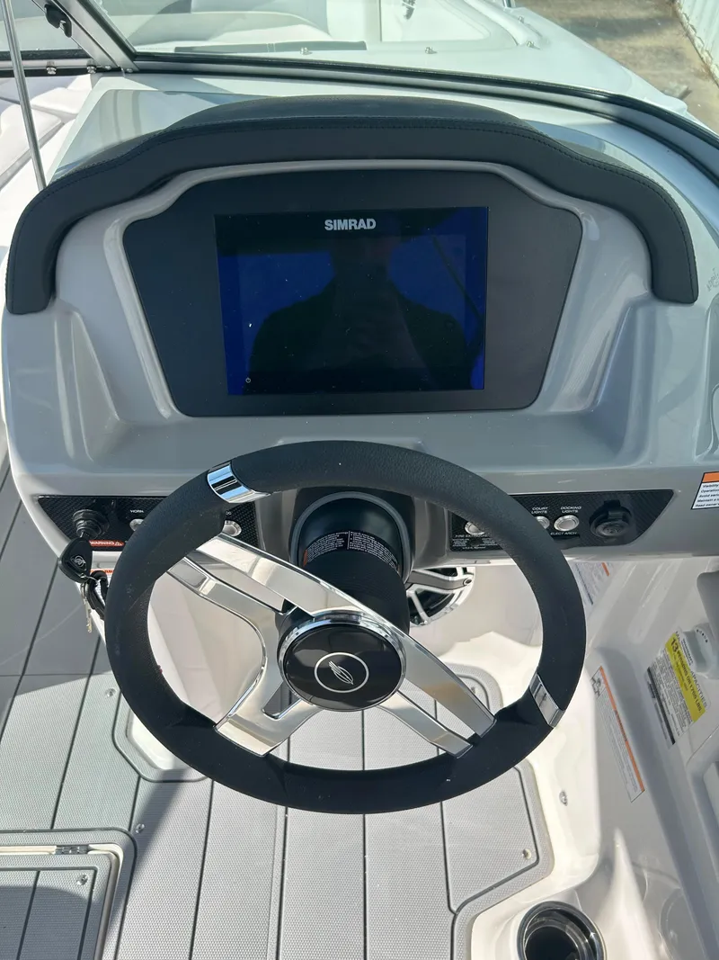 Slide: The Image of 2024 Chaparral 23 Surf boat dashboard with Simrad display and steering wheel. - 6