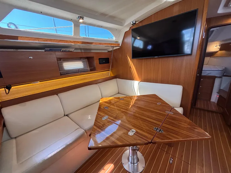 Slide: The Image of Interior of 2019 Catalina 385 sailboat with wooden table, white seating, and mounted TV. - 23