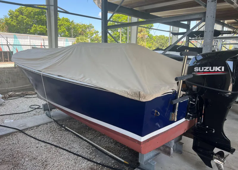 Slide: The Image of 1999 Northern Bay Center Console boat with Suzuki outboard motor, covered and stored in a boatyard. - 8