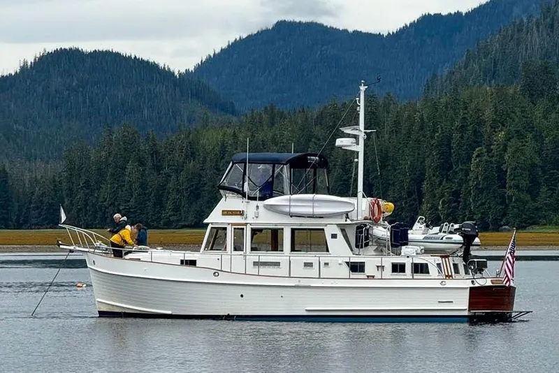 Slide: The Image of Grand Banks 46 Classic yacht from 2002 on a serene lake with forested mountains. - 1