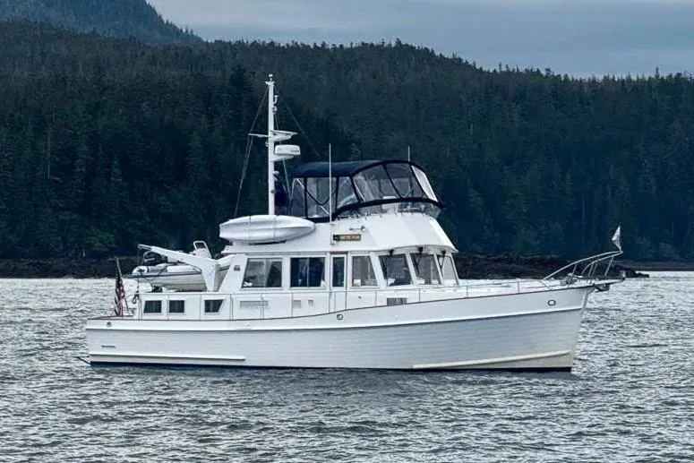 Slide: The Image of 2002 Grand Banks 46 Classic yacht on water, surrounded by forested landscape. - 54