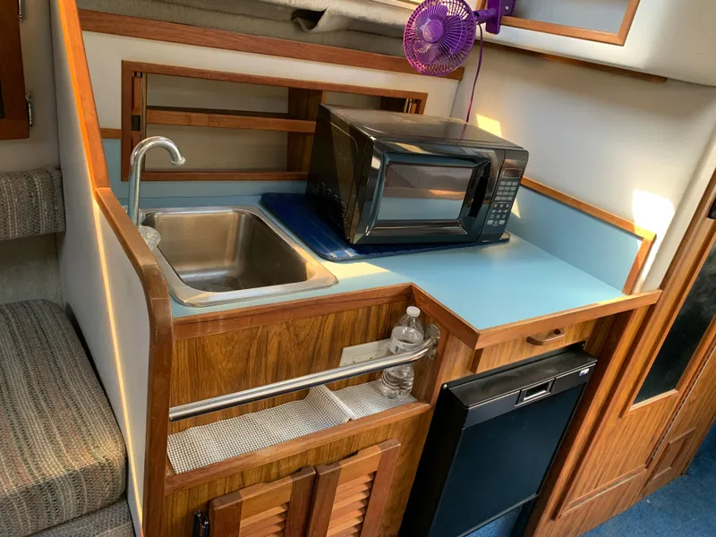 Slide: The Image of 1987 Sea Ray 268 Sundancer kitchenette with sink, microwave, and mini-fridge. - 4
