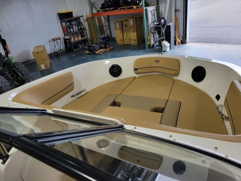 Slide: The Image of 2024 Bayliner VR5 boat interior with tan seating in a garage. - 11