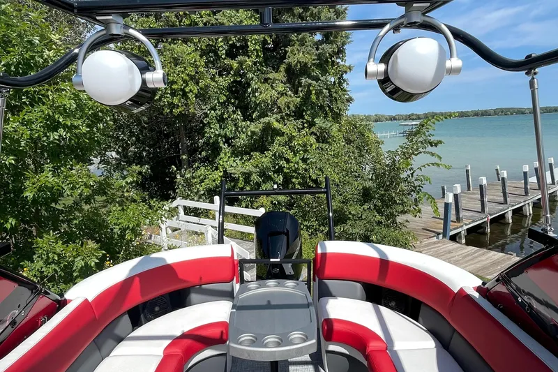 Slide: The Image of 2023 Berkshire 23 RFX STS pontoon boat with red and white seating, docked by a scenic lake. - 6