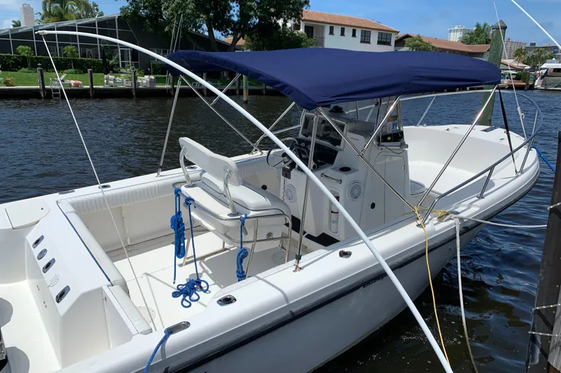 Slide: The Image of 1999 Boston Whaler Outrage 23 boat docked with blue canopy. - 2