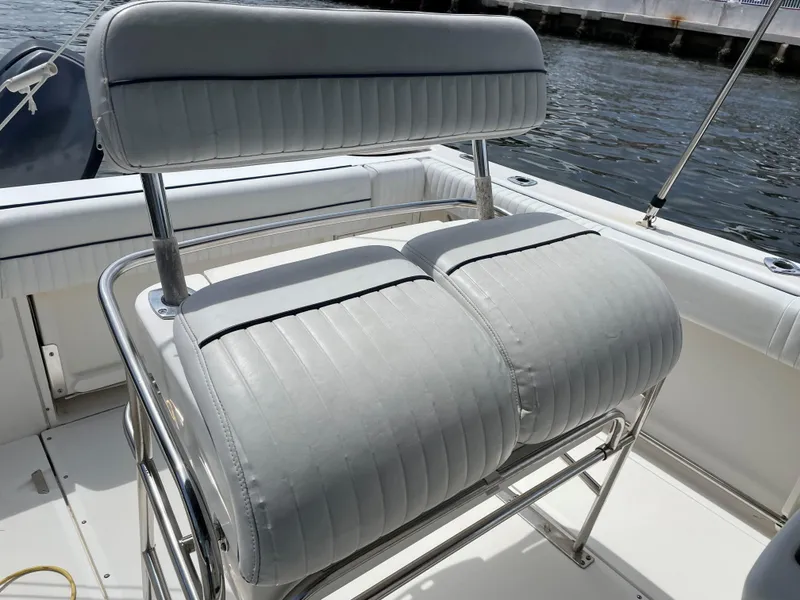 Slide: The Image of 1999 Boston Whaler Outrage 23 boat seating with white cushioned seats by the water. - 7