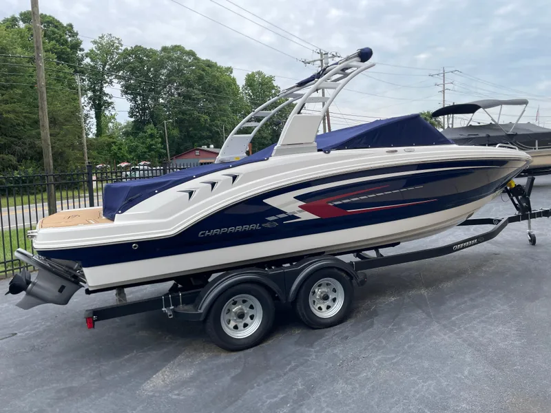 The Image of 2025 Chaparral 23 SSi boat on trailer in showroom, sleek design, white and black accents. - 0