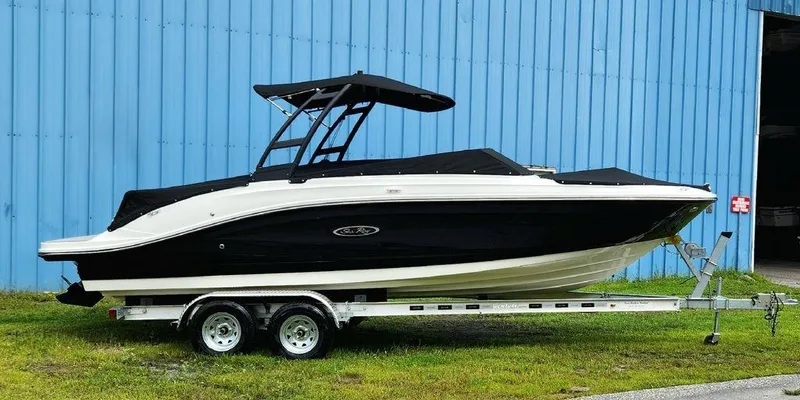 The Image of 2024 Sea Ray 230 SPX boat on a trailer, parked near a blue building. - 1