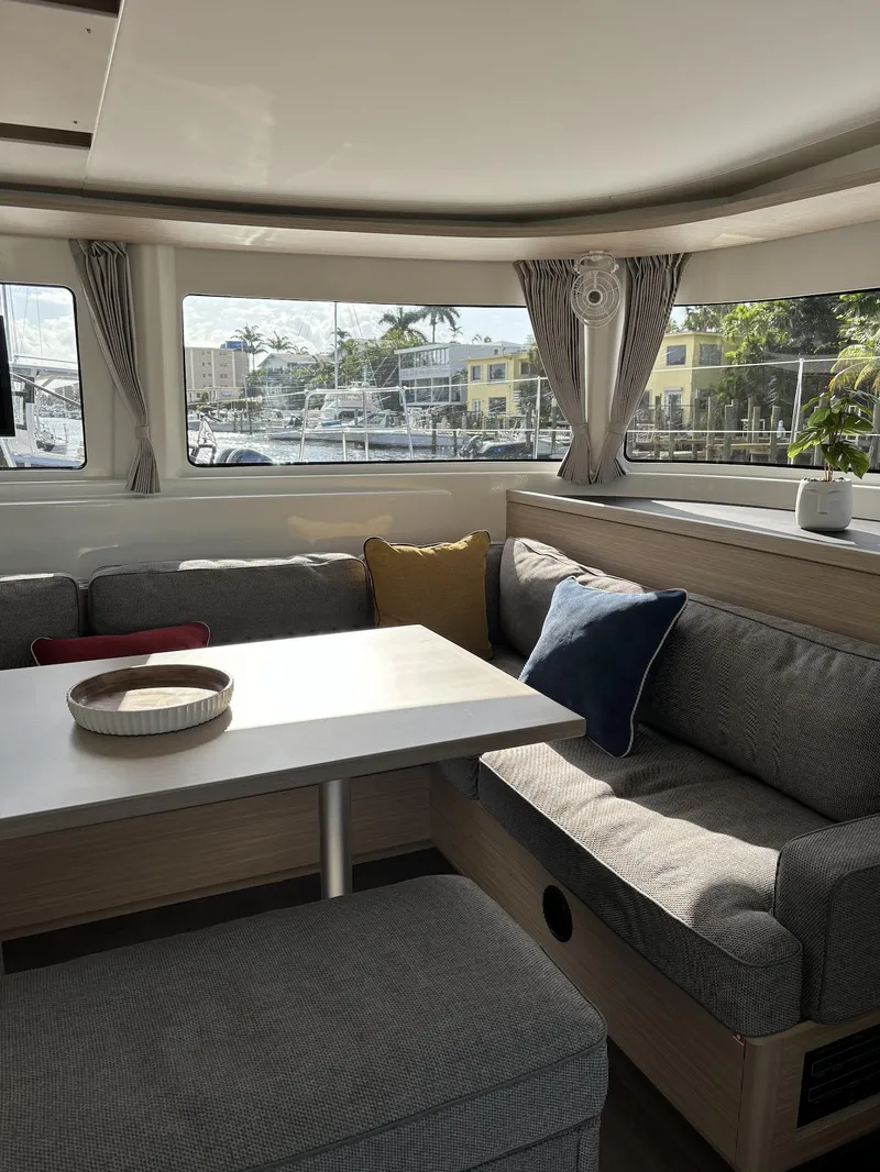 Slide: The Image of 2024 Lagoon 46 yacht interior with wooden table and cushioned seating. - 29