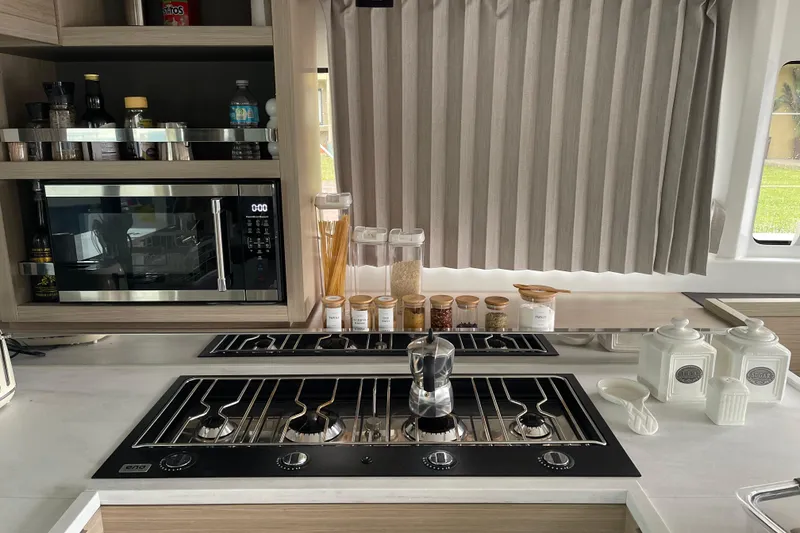 Slide: The Image of Modern kitchen in 2024 Lagoon 46 yacht with stove, microwave, and organized spices. - 43
