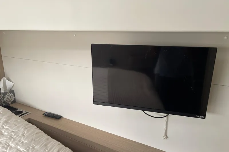 Slide: The Image of Wall-mounted TV in a 2024 Lagoon 46 yacht interior, with remote and tissues nearby. - 44