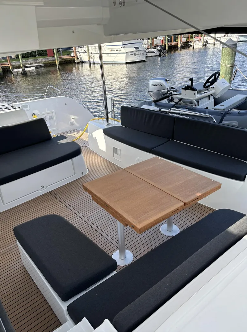 Slide: The Image of 2024 Lagoon 46 catamaran docked in a marina, showcasing its spacious deck and netting. - 5