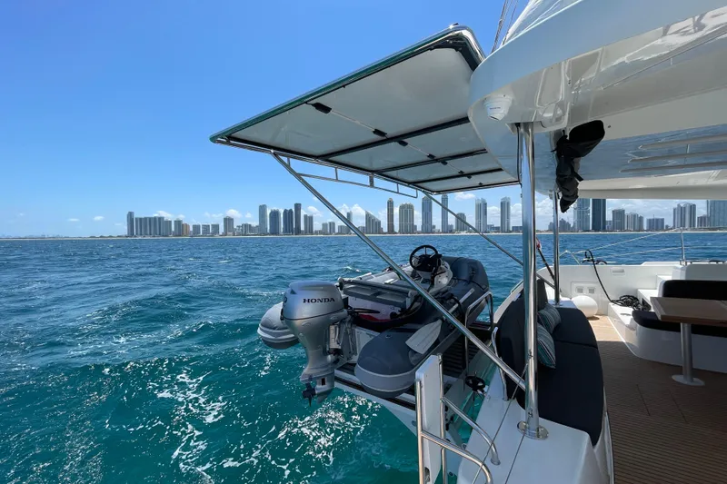 Slide: The Image of 2024 Lagoon 46 catamaran with city skyline, ocean view, and inflatable boat on deck. - 55