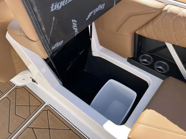 Slide: The Image of 2023 Tigé Z3 boat interior storage compartment with tan seats and white bin. - 13