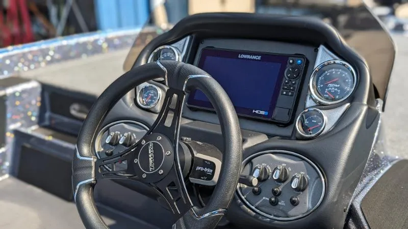 Slide: The Image of 2024 Triton 18 TrX boat dashboard with Lowrance HDS display and steering wheel. - 2