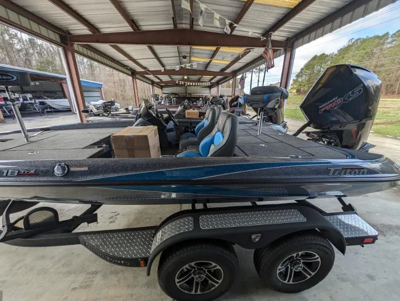 Slide: The Image of 2024 Triton 18 TrX bass boat on a trailer in a covered storage area. - 21