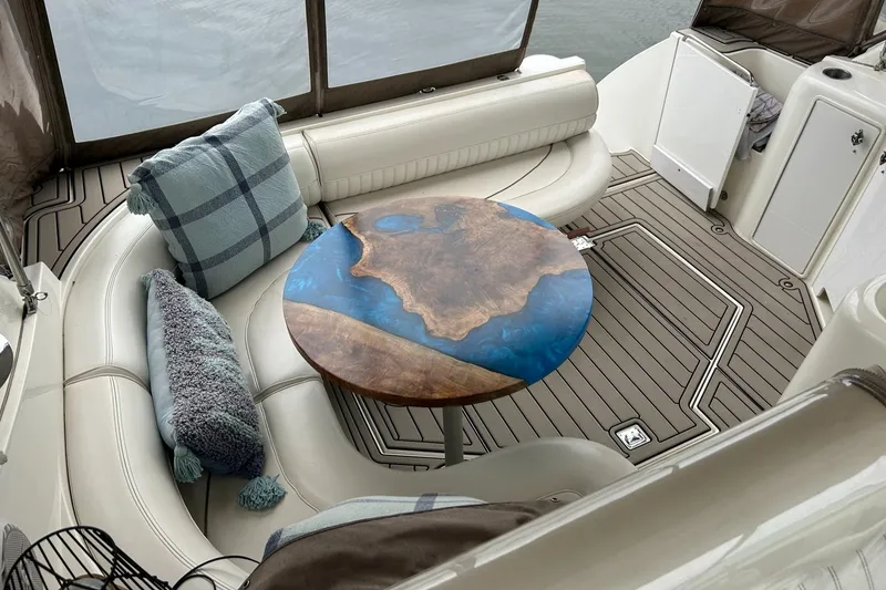 Slide: The Image of 2000 Cruisers Yachts 3870 Express interior with custom wood and resin table, plush seating, and pillows. - 21