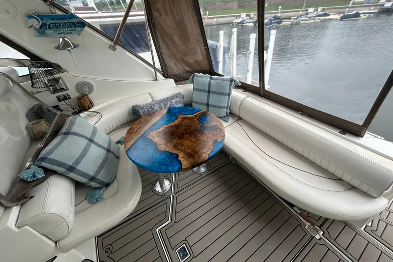 Slide: The Image of 2000 Cruisers Yachts 3870 Express interior with plush seating and unique wooden table. - 23