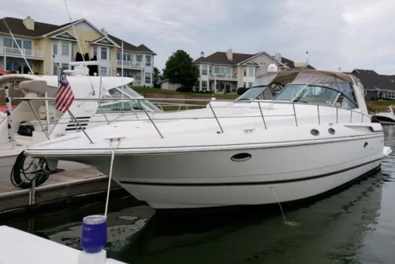Slide: The Image of 2000 Cruisers Yachts 3870 Express docked at a marina with waterfront homes in the background. - 3