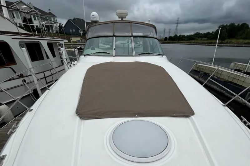 Slide: The Image of 2000 Cruisers Yachts 3870 Express docked, front deck view with brown cover. - 40