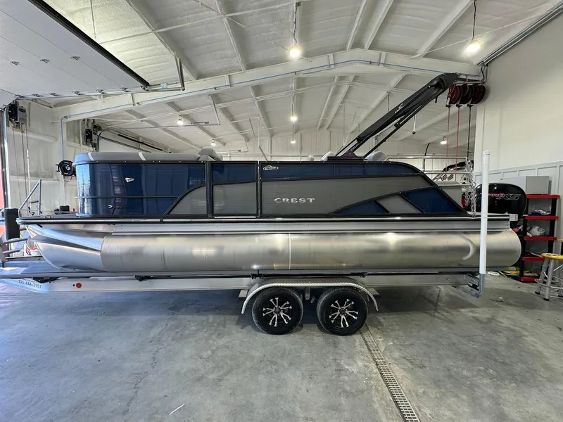 Slide: The Image of 2023 Crest Classic Platinum 220 pontoon boat in a spacious indoor garage. - 1