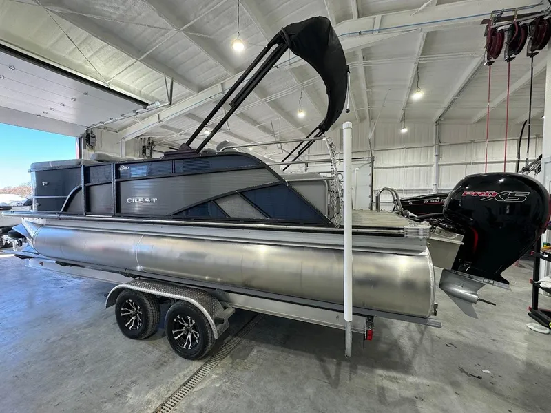 Slide: The Image of 2023 Crest Classic Platinum 220 pontoon boat in a showroom, side view. - 2