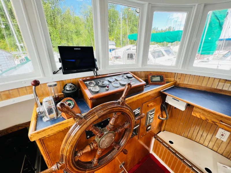Slide: The Image of 1955 Colin Archer 42 boat helm with wooden wheel, control panel, and navigation equipment. - 14