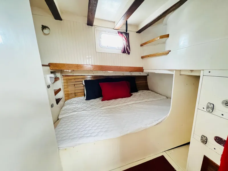 Slide: The Image of Cozy cabin bedroom in a 1955 Colin Archer 42 sailboat with white bedding and wooden accents. - 29