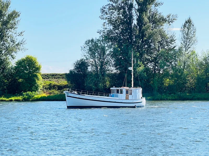 Slide: The Image of Vintage 1955 Colin Archer 42 boat on a serene river with lush greenery. - 39