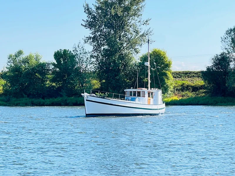 Slide: The Image of Classic 1955 Colin Archer 42 boat on a serene lake with lush greenery. - 41