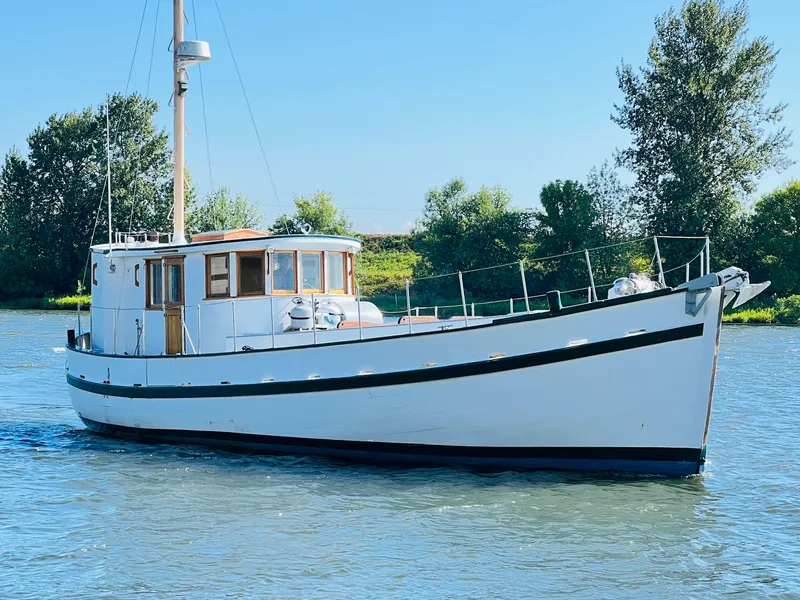 Slide: The Image of 1955 Colin Archer 42 boat on calm water with trees in the background. - 48