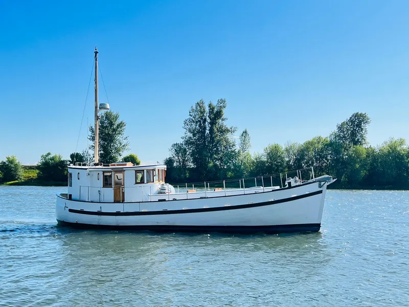 Slide: The Image of 1955 Colin Archer 42 boat cruising on a calm river with trees in the background. - 49