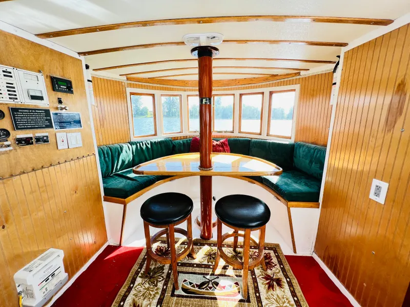 Slide: The Image of 1955 Colin Archer 42 boat interior with wooden paneling, green seating, and round table. - 7