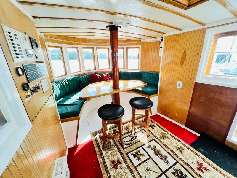 Slide: The Image of Cozy interior of a 1955 Colin Archer 42 boat with wooden paneling and green seating. - 8