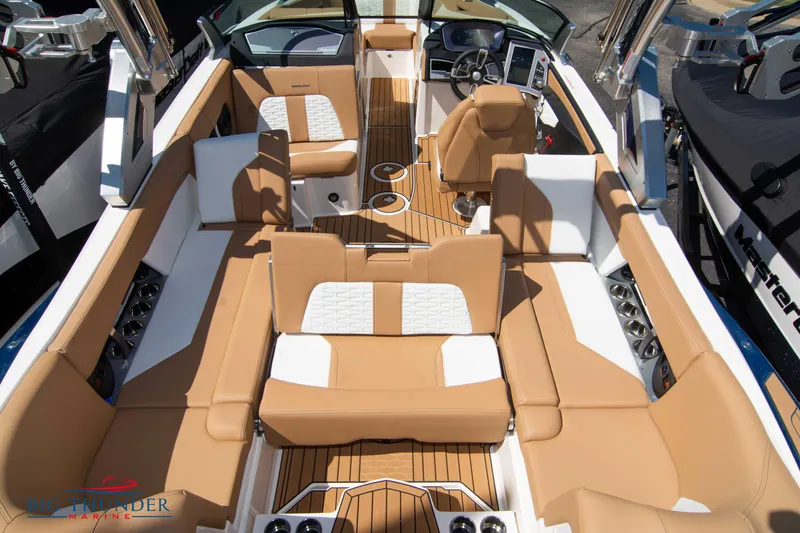 Slide: The Image of 2023 MasterCraft X24 boat interior with tan and white seating, modern dashboard, and spacious layout. - 15