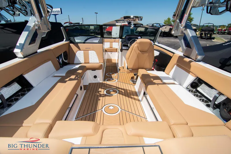 Slide: The Image of 2023 MasterCraft X24 boat interior with tan and white seating, teak flooring, and Big Thunder Marine logo. - 16