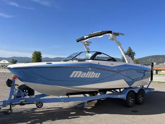 Slide: The Image of 2024 Malibu 22 LSV boat on trailer, blue and white, parked outdoors. - 3