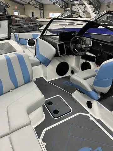 Slide: The Image of 2024 Malibu 22 LSV boat interior with blue and gray seating, modern dashboard, and spacious layout. - 7
