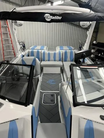 Slide: The Image of 2024 Malibu 22 LSV boat interior with blue and white seating in a garage. - 9