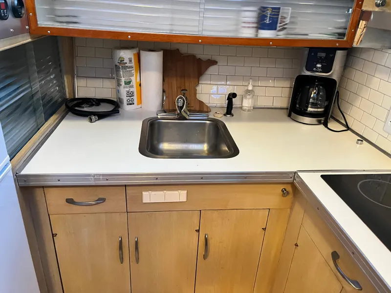 Slide: The Image of 1962 Chris-Craft Constellation kitchen with sink, coffee maker, and wooden cabinets. - 12