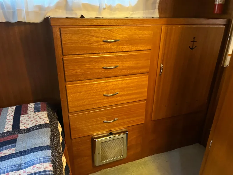 Slide: The Image of 1962 Chris-Craft Constellation interior with wooden drawers and cabinet, featuring a nautical anchor design. - 26
